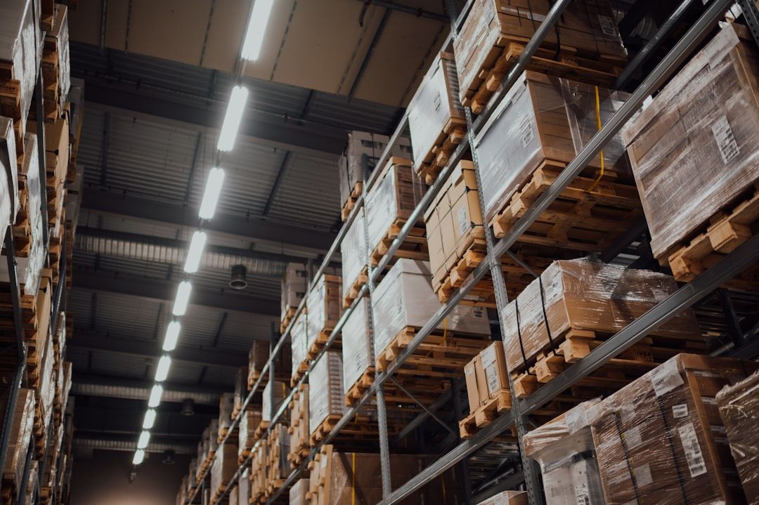 Höga lagerhyllor fyllda med plastinpackat gods i ett logistikcenter.