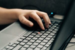 Hand som skriver på ett laptop-tangentbord med röd styrpinne